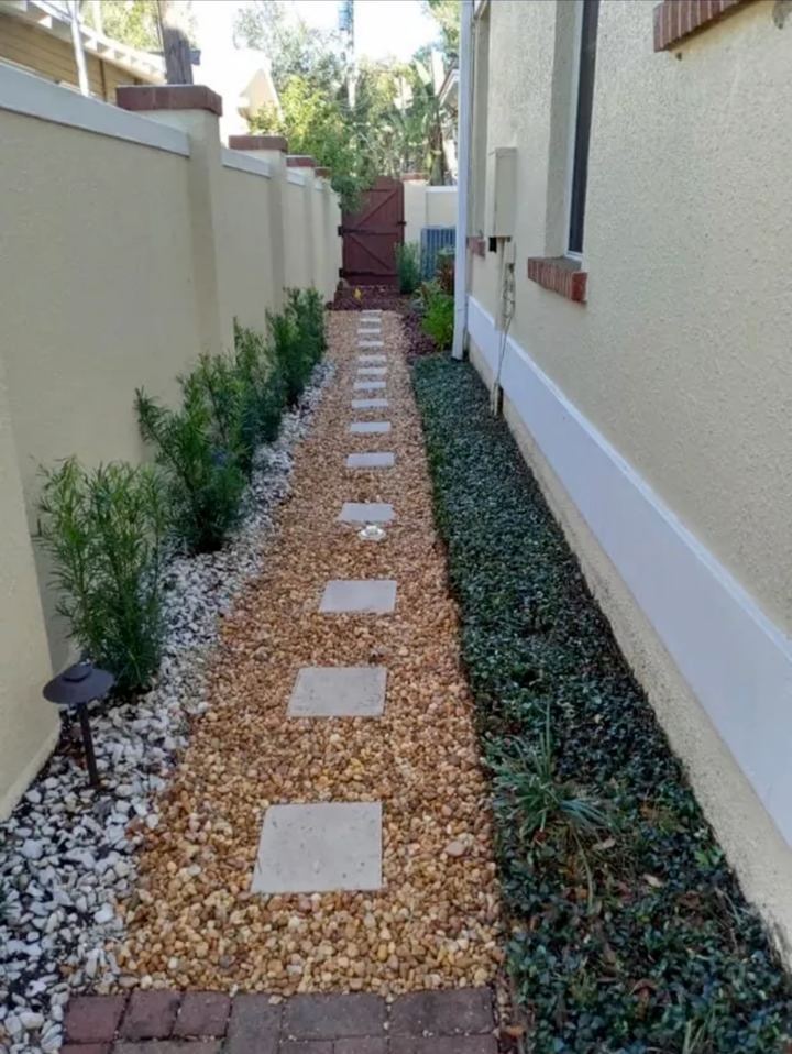 Side yard finished with a stepping-stone path, gravel and shrubs along the wall